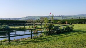 A serene landscape with a pond, grassy areas, and a distant hill. - The Wagon House (Launceston)