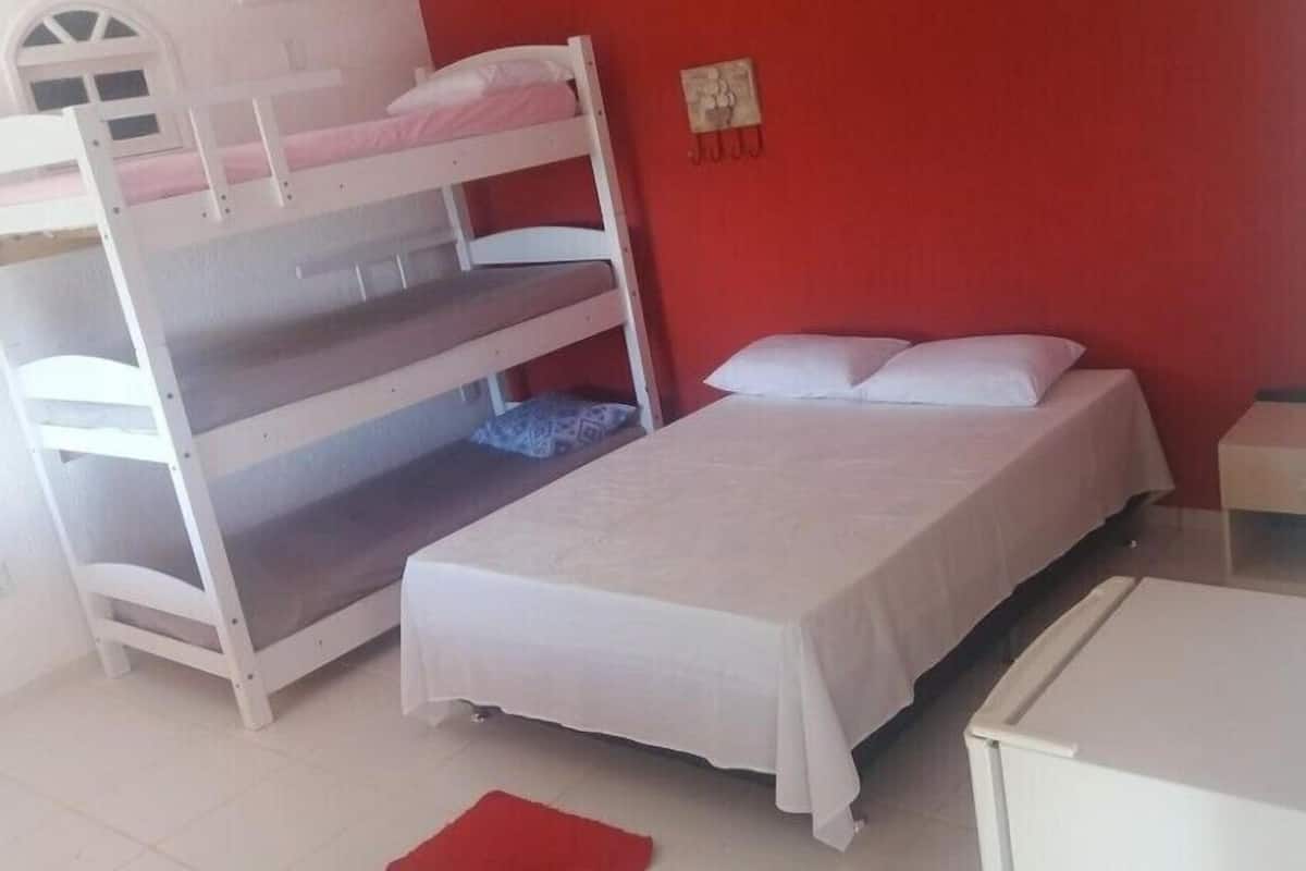 A room with bunk beds, a single bed, a nightstand, and a desk.