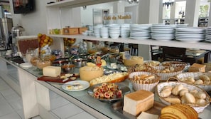 A buffet setup with various food items and utensils. - Soder Hotel (Santa Cruz do Sul)