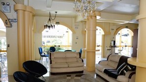 A spacious lobby with a beige sofa, a black chair, and a chandelier.