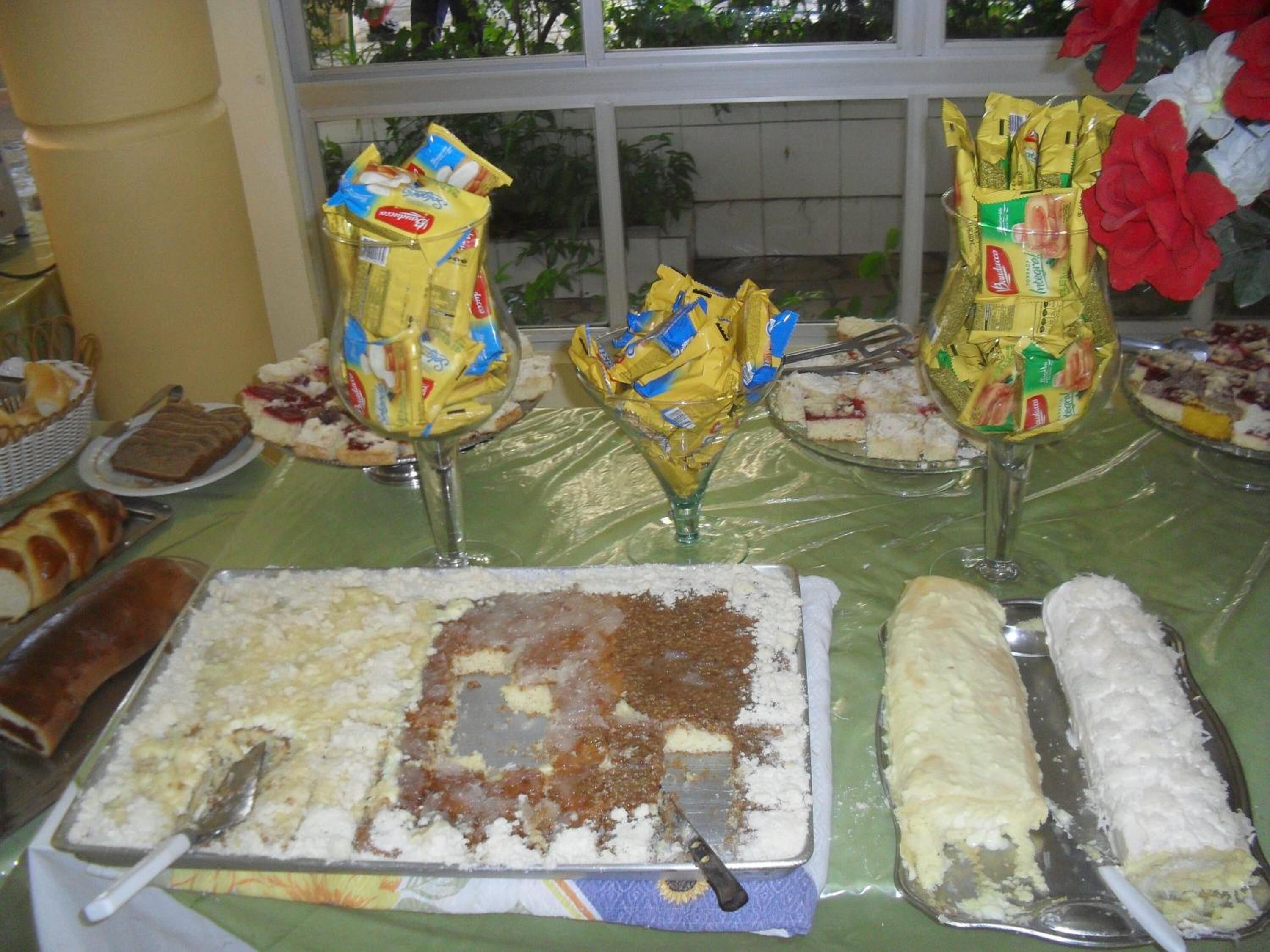 Une table de buffet proposant divers plats, notamment des gâteaux et des pâtisseries, ainsi que quelques condiments présentés dans des récipients en verre.