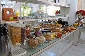 A buffet with various food items and containers, including cereal, nuts, and condiments. - Soder Hotel (Santa Cruz do Sul)