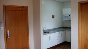 Una cocina compacta con armarios blancos, un microondas integrado y un lavamanos.