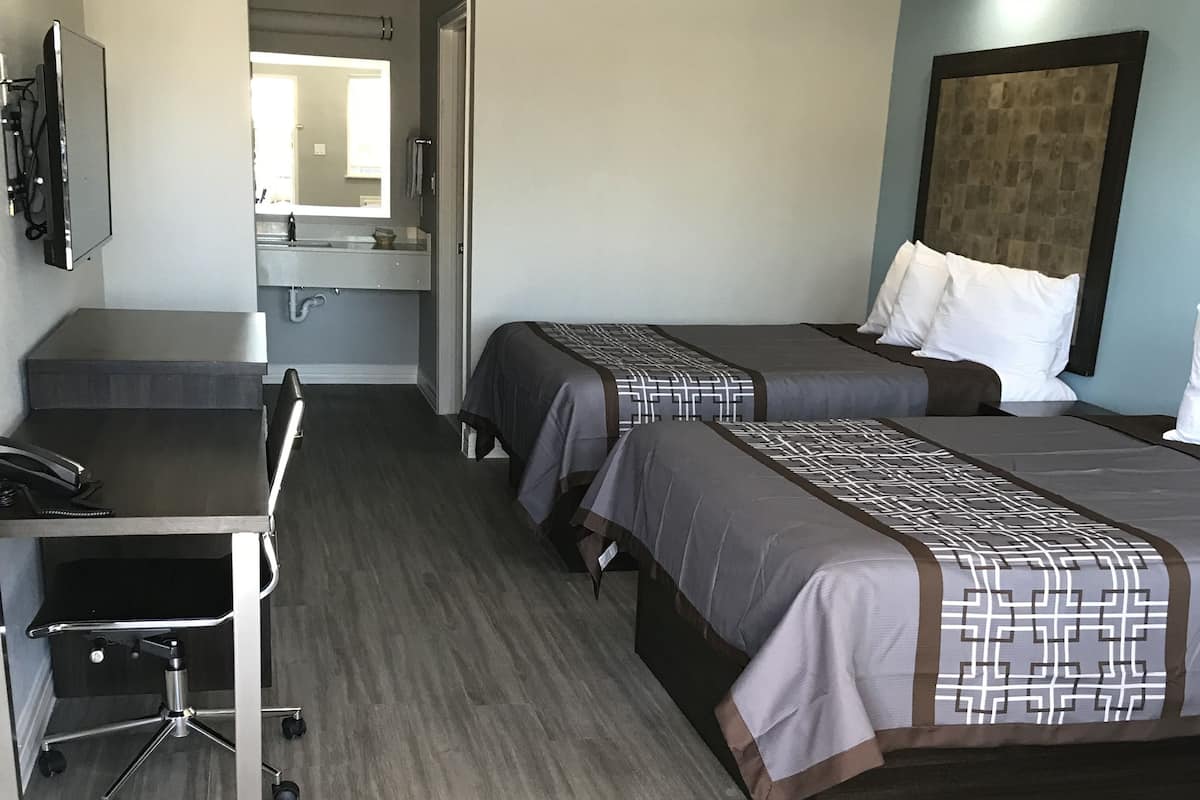 Habitación de hotel con dos camas, un escritorio y un televisor.