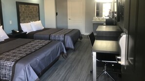 A hotel room with two beds, a desk, a chair, a TV, and a bathroom door. - The Residency Suites (Houston)