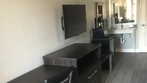A modern kitchen with a dark countertop, a built-in oven, and a microwave. - The Residency Suites (Houston)