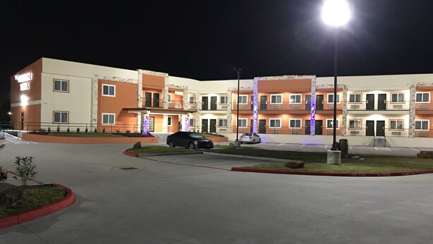 A multi-story hotel with a parking lot, illuminated by street lamps. - The Residency Suites (Houston)