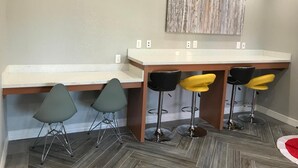 A kitchen with a bar area, grey chairs, and a wooden countertop. - The Residency Suites (Houston)