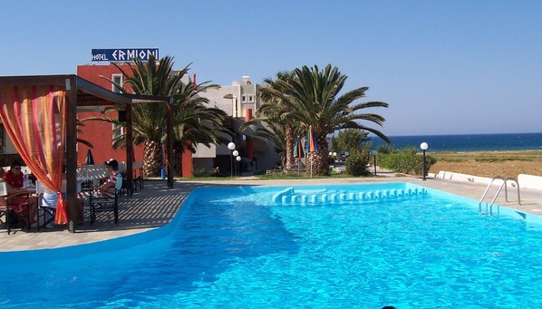 A hotel named 'ERMIONI' with a swimming pool, palm trees, and a view of the sea. - Ermioni Hotel (Apokoronas)