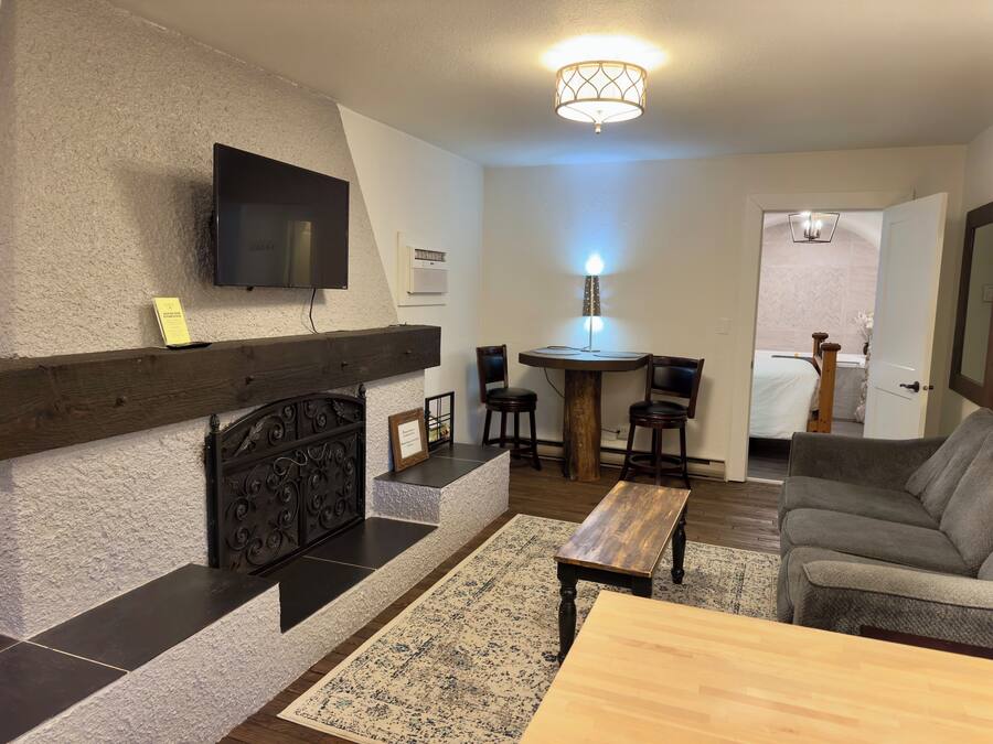 Un salon avec une cheminée, un téléviseur fixé au mur, une table à manger avec des chaises et un canapé.