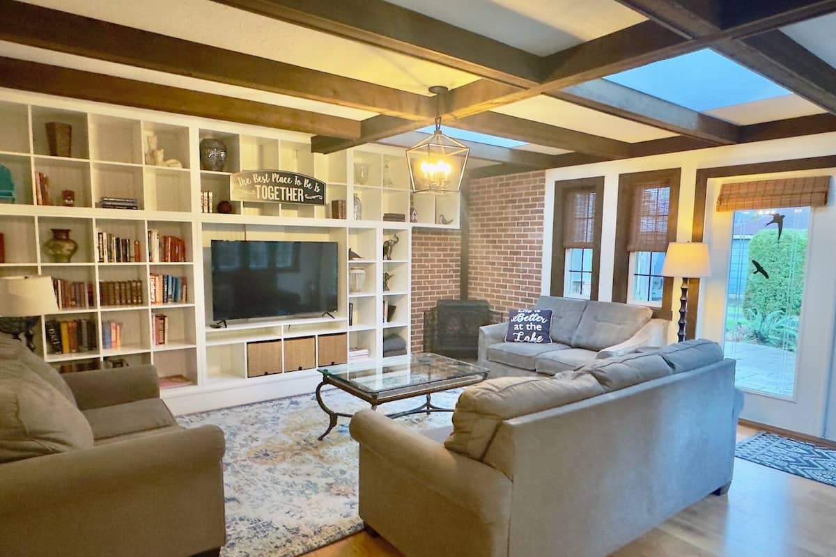 A living room with a TV, sofas, a bookshelf, and a fireplace.