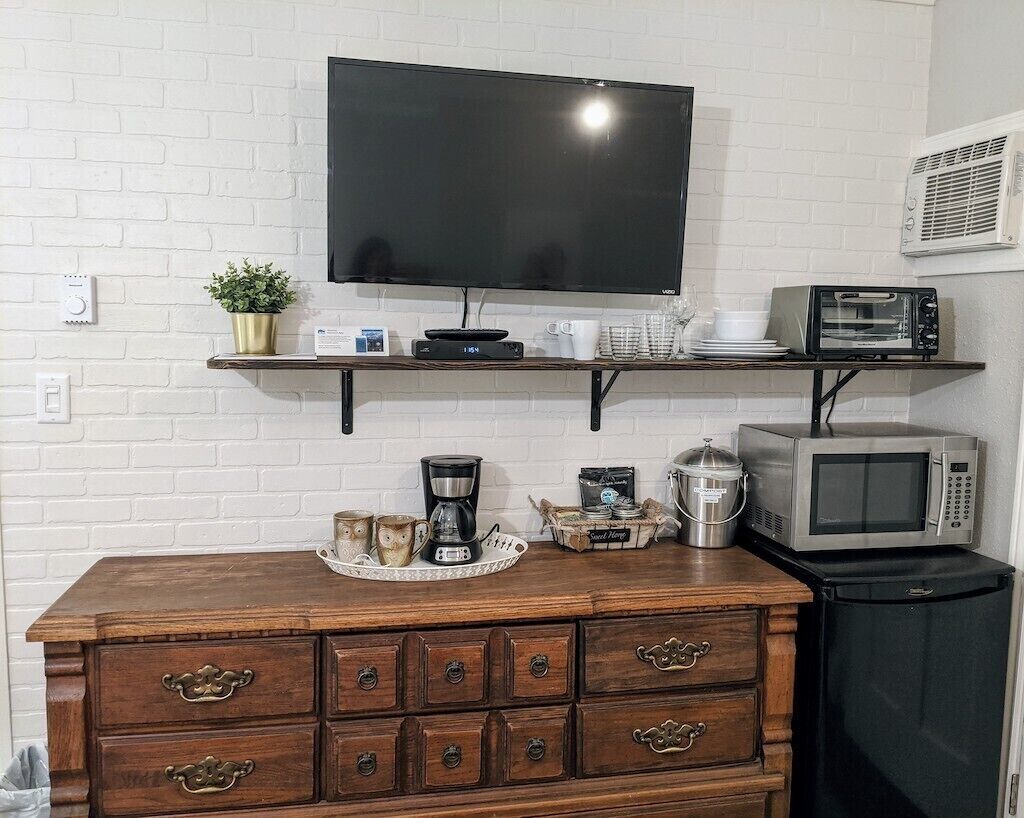 Eine Küchenzeile mit Flachbildfernseher, Mikrowelle, Toaster, Kaffeemaschine und kleinem Kühlschrank.