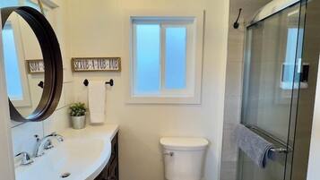 Un bagno con lavandino bianco, WC, doccia e finestra.