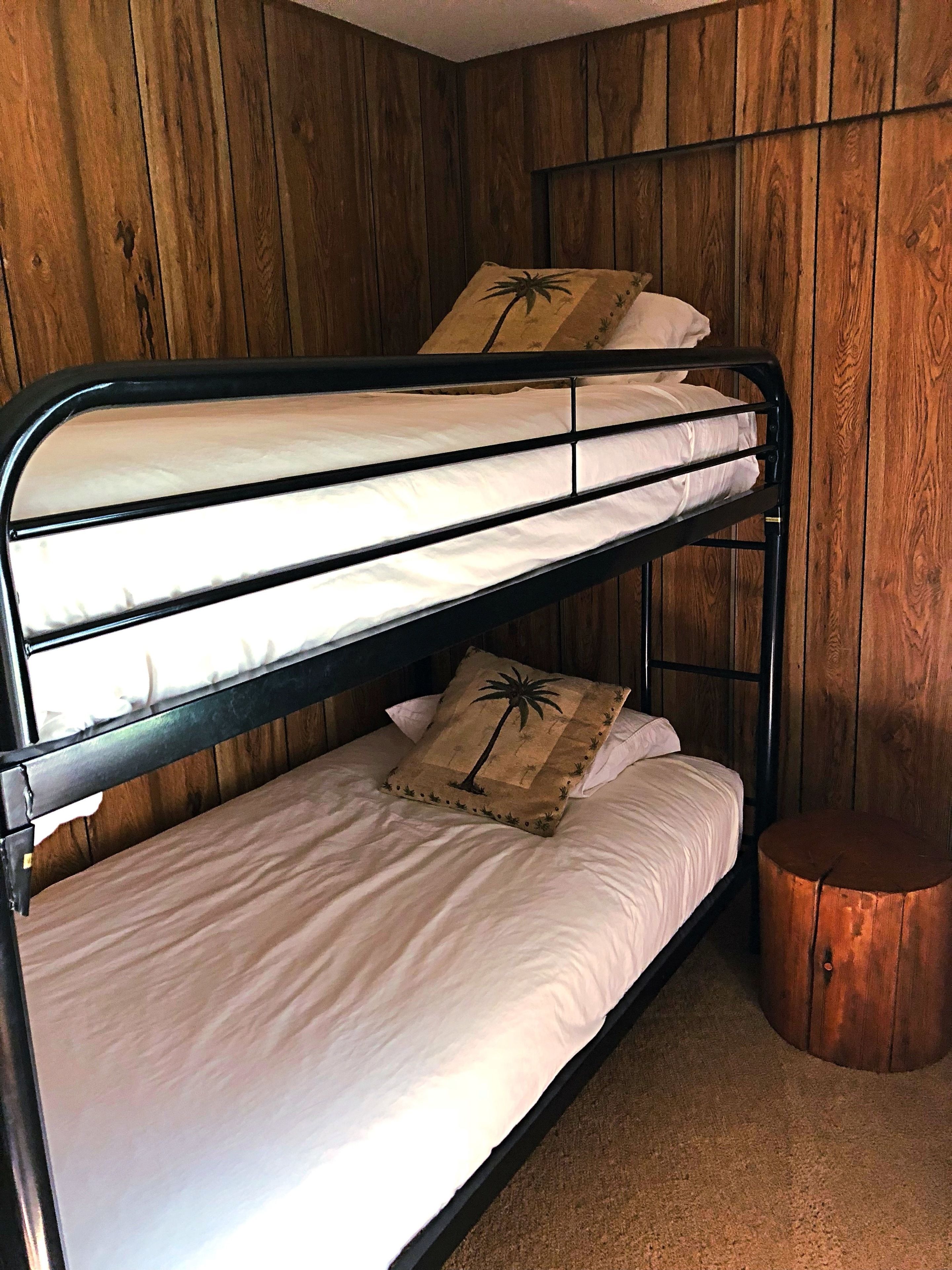 A bunk bed with two levels, each with a pillow featuring a palm tree design.