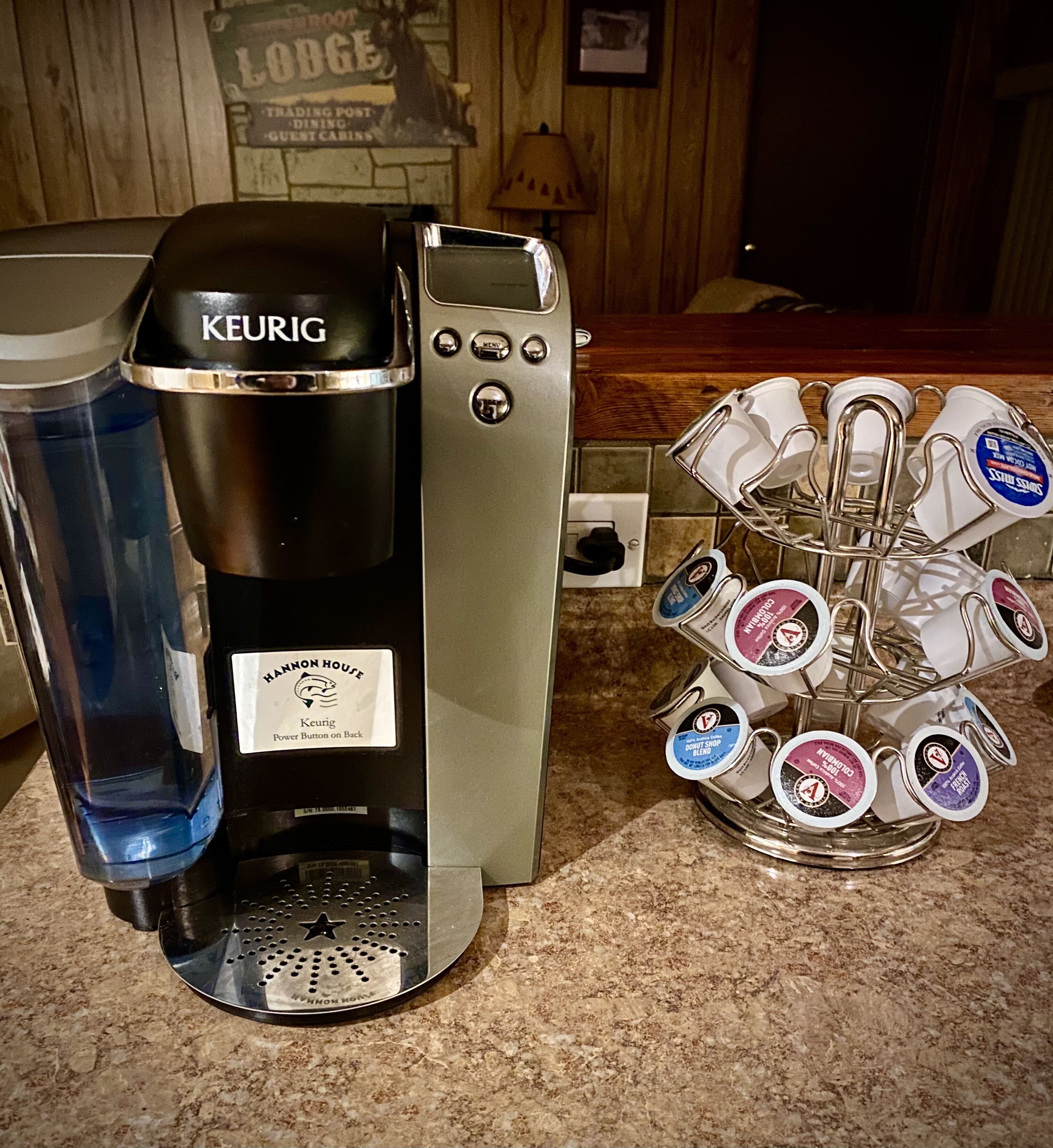 A Keurig coffee maker with a water reservoir and a mug holder with various coffee pods.