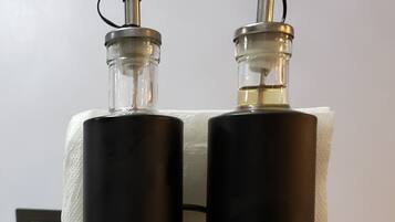 Two bottles of vinegar on a glass table against a white wall.