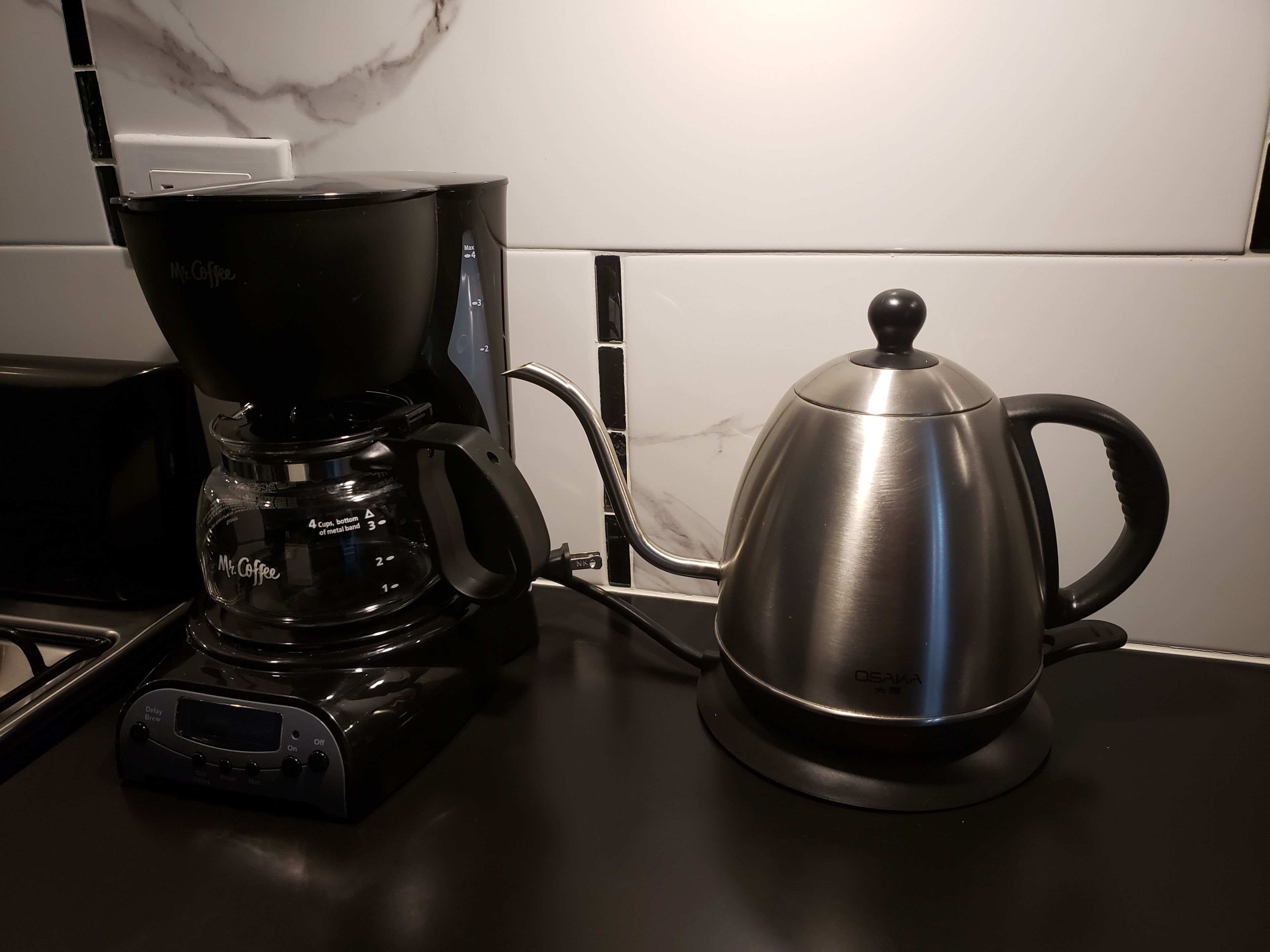 A coffee maker and a stainless steel pot on a kitchen counter.