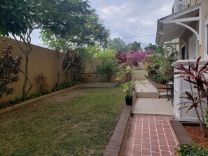 Un jardín residencial con un sendero pavimentado que conduce a un edificio blanco.