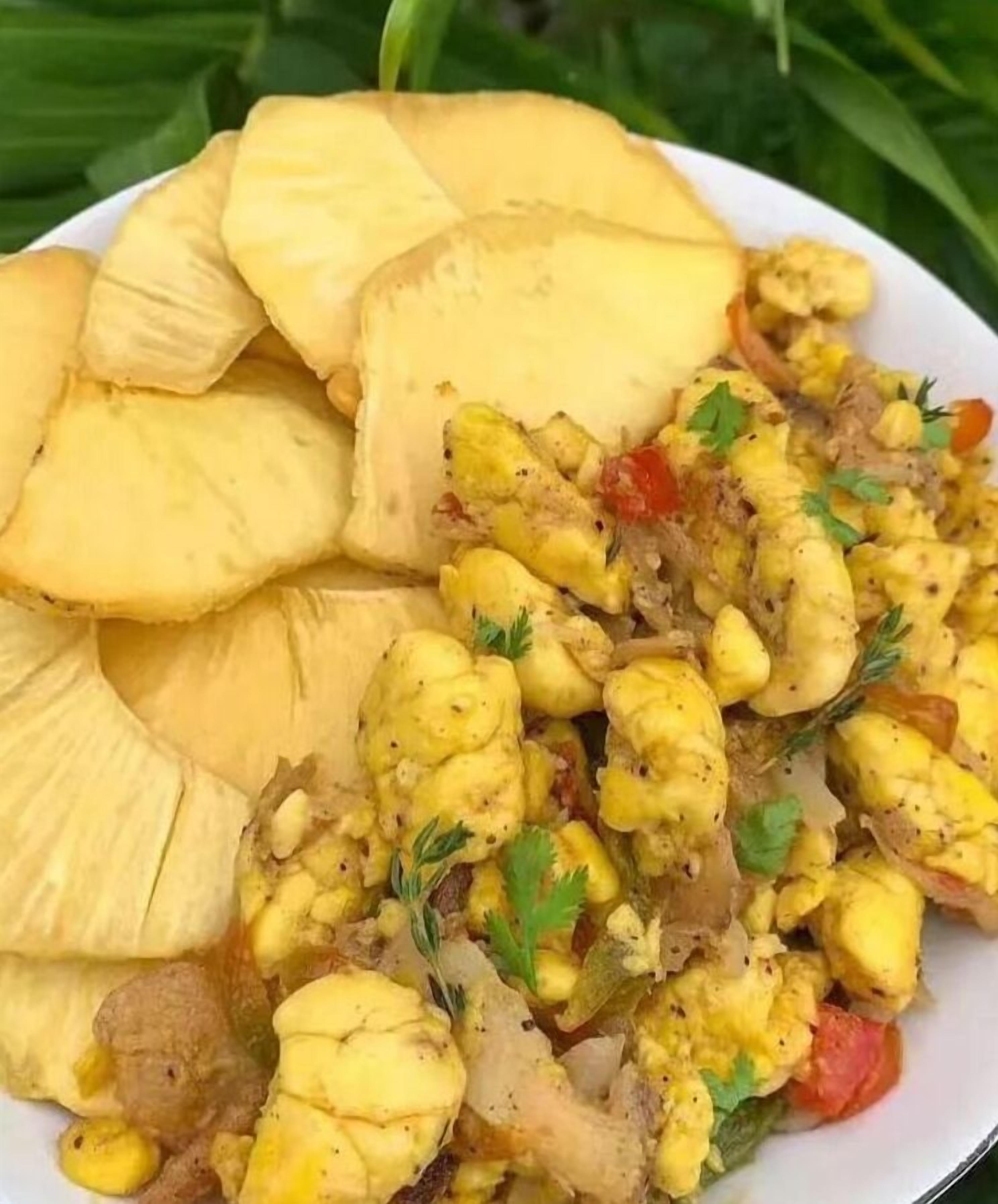 Un piatto di cibo con patate a fette e un curry guarnito con erbe aromatiche.