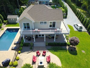 A two-story house with a swimming pool, patio furniture, and a well-maintained lawn. - Cove View Manor of Sag Harbor (Sag Harbor)