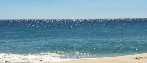 A beach with clear blue water and a sandy shore.