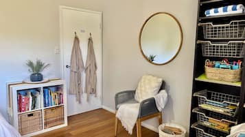 A room with a bookshelf, a chair, a mirror, and a storage unit.