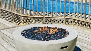 A poolside area with a fire pit and a wooden deck. - Private Heated Pool • 5BR/3BA • Near Beaches and Nickerson Park (Brewster)
