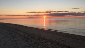 A beach at sunset with calm waters reflecting the sky. - Private Heated Pool • 5BR/3BA • Near Beaches and Nickerson Park (Brewster)