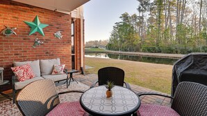 An outdoor patio with a brick wall, a star decoration, and a view of a lake and trees. - Tupelo Bay Golf Resort Condo - 1 Mile to Beach! (Murrells Inlet)