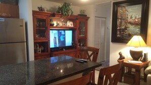 Eine Küche mit Granit-Arbeitsplatten, Holzschränken, einem Kühlschrank und einem Fernseher.
