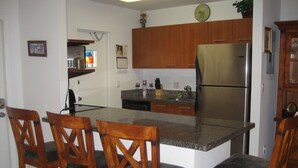 Eine Küche mit Holzausstattung, einem Edelstahlkühlschrank und einer Arbeitsplatte aus Granit.