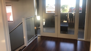 A hallway with a glass door leading to an outdoor area.