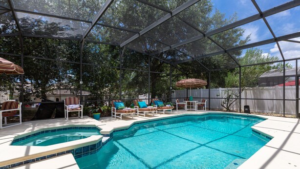 A backyard with a swimming pool, lounge chairs, and umbrellas.