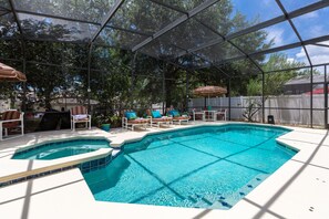 A backyard with a swimming pool, lounge chairs, and umbrellas. - Magical Family Villa: 8-Bdrm, 5 Themed, Pool, Spa, Game Room, Arcade, Movie (Davenport)