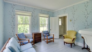 A room with light blue walls, white wooden flooring, and two windows. There are three wooden chairs with blue cushions and a yellow armchair. A white door is visible in the background. - Mattapoisett Home on 7 Acres w/ Private Beach! (Mattapoisett)