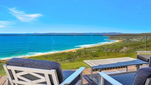 En balkon med udsigt over strand og hav.