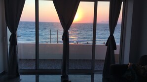 Une pièce dotée d’une grande fenêtre donnant sur la mer au coucher du soleil.