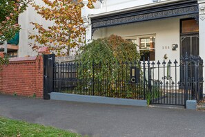 A white building with a black iron gate and a brick wall. - South Melbourne terrace house.Short walk to Grand Prix,MSAC,Market,Pet friendly (South Melbourne)