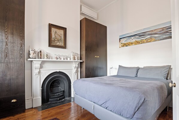 A bedroom with a bed, a fireplace, a dark wardrobe, and a painting on the wall. - South Melbourne terrace house.Short walk to Grand Prix,MSAC,Market,Pet friendly (South Melbourne)