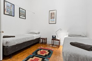 A room with two single beds, a small table with a lamp, and a rug on the floor. - South Melbourne terrace house.Short walk to Grand Prix,MSAC,Market,Pet friendly (South Melbourne)