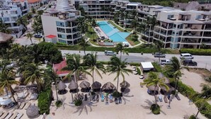 A resort with a swimming pool, beach area with sun loungers, and multiple hotel buildings. - Ground Floor private Condo at The Elements by BRIC (Playa del Carmen)