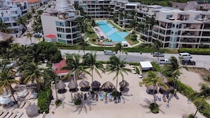 Ein Resort mit Schwimmbad, Strandbereich inklusive Liegen und mehreren Hotelgebäuden.