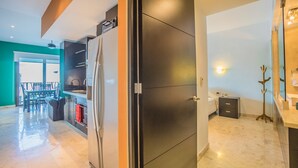 A modern kitchen with a large refrigerator, a dining area with chairs and a table, and a bathroom with a sink and mirror. - Great 1 Bedroom Studio at Las Brisas by BRIC Vacation Rentals in Playa del Carmen (Playa del Carmen)