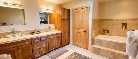 A modern bathroom with a large mirror, wooden cabinets, a bathtub, and a shower area.