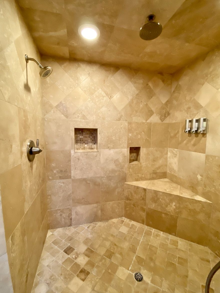 A shower with a handheld showerhead, a wall-mounted faucet, and a tiled floor.