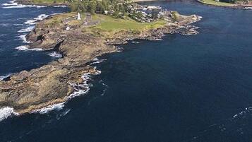 An aerial view of a rugged coastline with rocky terrain and a lighthouse.