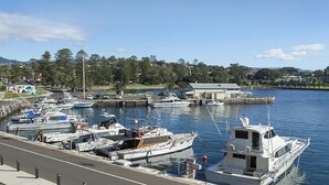 A marina with several boats docked, a clear sky, and a building in the background. - Shoreline 501 Sebel Kiama (Kiama)