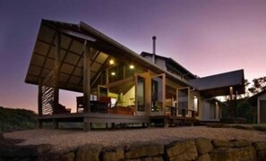Une maison moderne à architecture ouverte, dotée d’une grande terrasse et de nombreuses fenêtres.