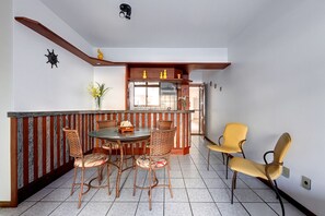 Cozy dining area with a round table and wicker chairs, plus a bar area with stools.