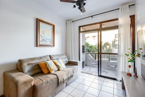 Relax in this stylish living room with a sofa, framed art, and sliding glass door leading to a balcony with a chair and table.